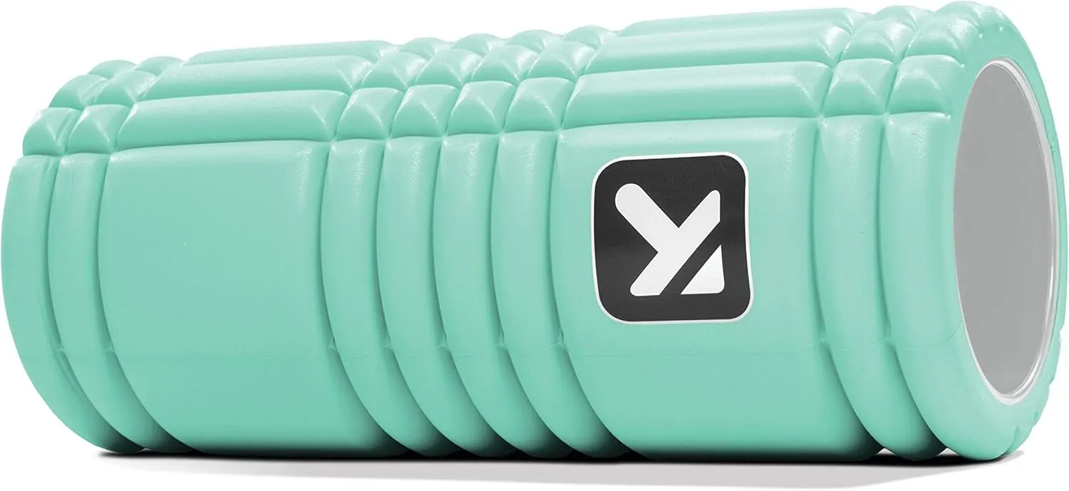 Close-up of a TriggerPoint GRID foam roller positioned under the TFL muscle just below the hip bone