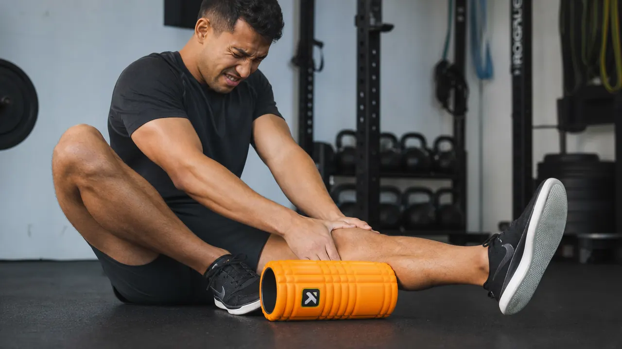 Person demonstrating incorrect calf foam rolling position on TriggerPoint GRID with visible tension in leg